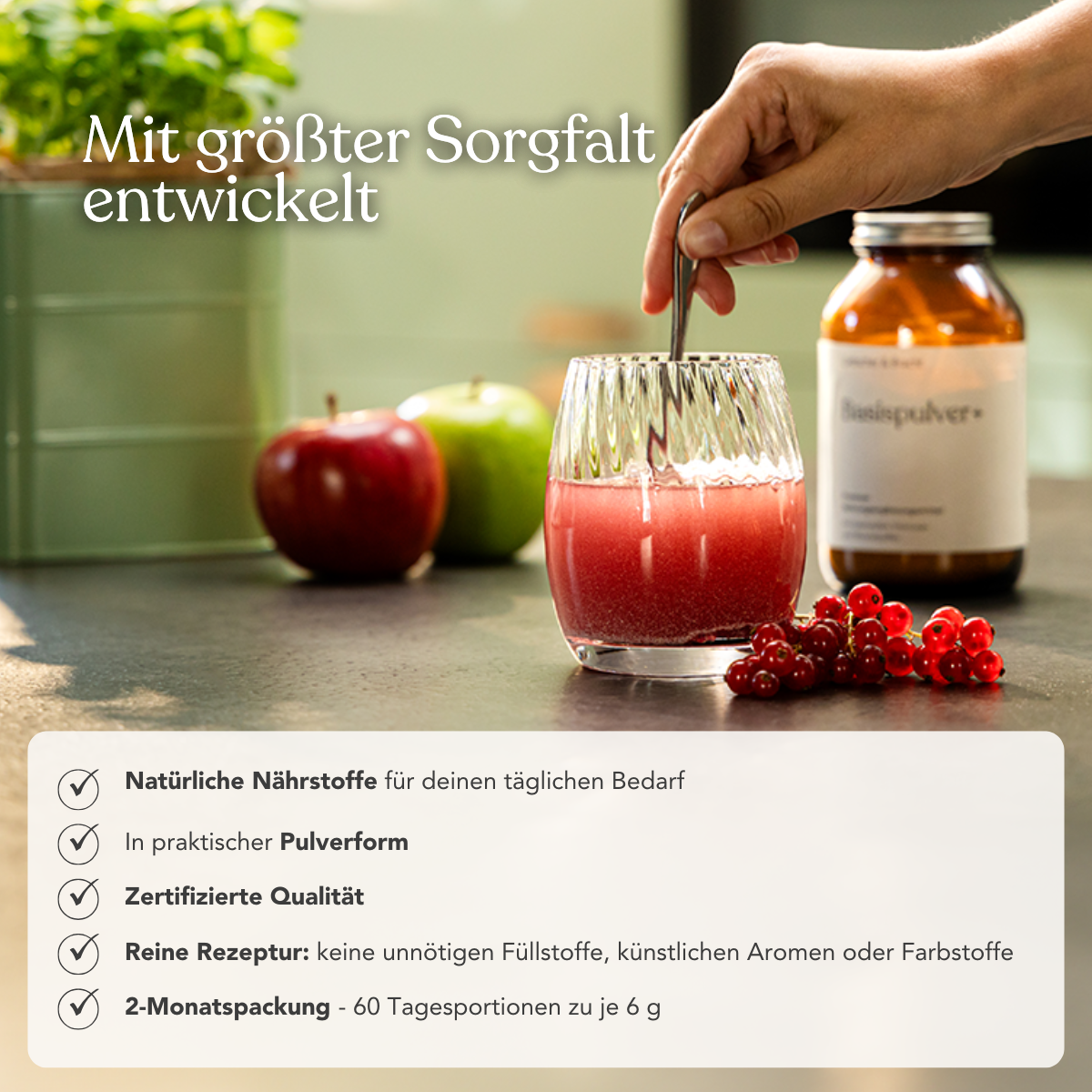 Eine Hand hält ein Glas mit rotem veganem Getränk auf einem Tisch, daneben Äpfel, rote Johannisbeeren und das ALL IN ONE - Arthro-Paket (Pulver+Kapseln) von Liebscher & Bracht - vitaminreich und besonders hochwertig.