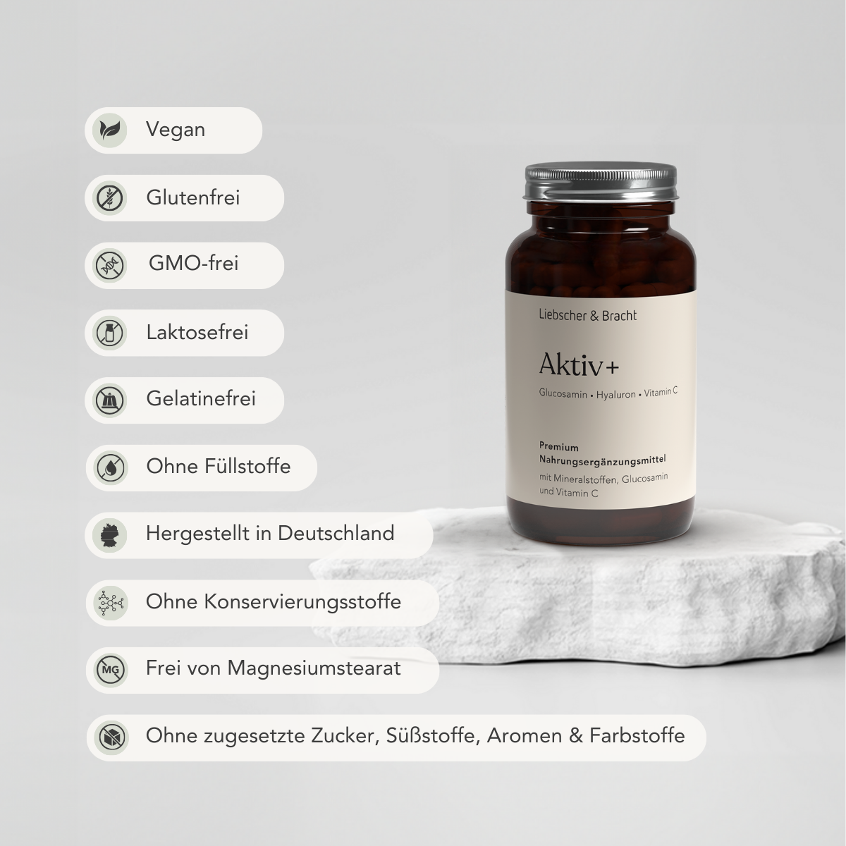 Auf einer weißen Steinplatte ruht eine braune Flasche Liebscher & Bracht Aktiv+ für 2 Monate mit Symbolen für vegan, glutenfrei, Vitamin C, umweltfreundliche Verpackung und ohne Füllstoffe, Konservierungsmittel oder Zuckerzusatz. Hergestellt in Deutschland.