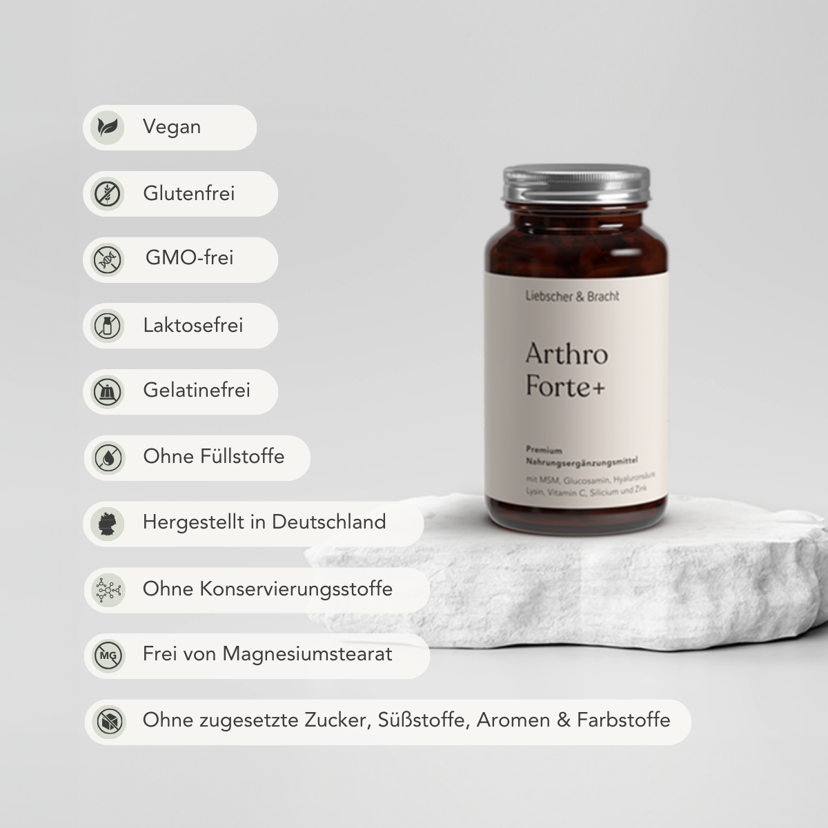 Eine braune Flasche Arthro Forte+ für 2 Monate von Liebscher & Bracht steht auf einer Steinplatte, auf der Symbole stehen: vegan, glutenfrei, GVO-frei, Glucosamin & Hyaluronsäure, laktosefrei, ohne Konservierungs- und Füllstoffe, made in Germany.