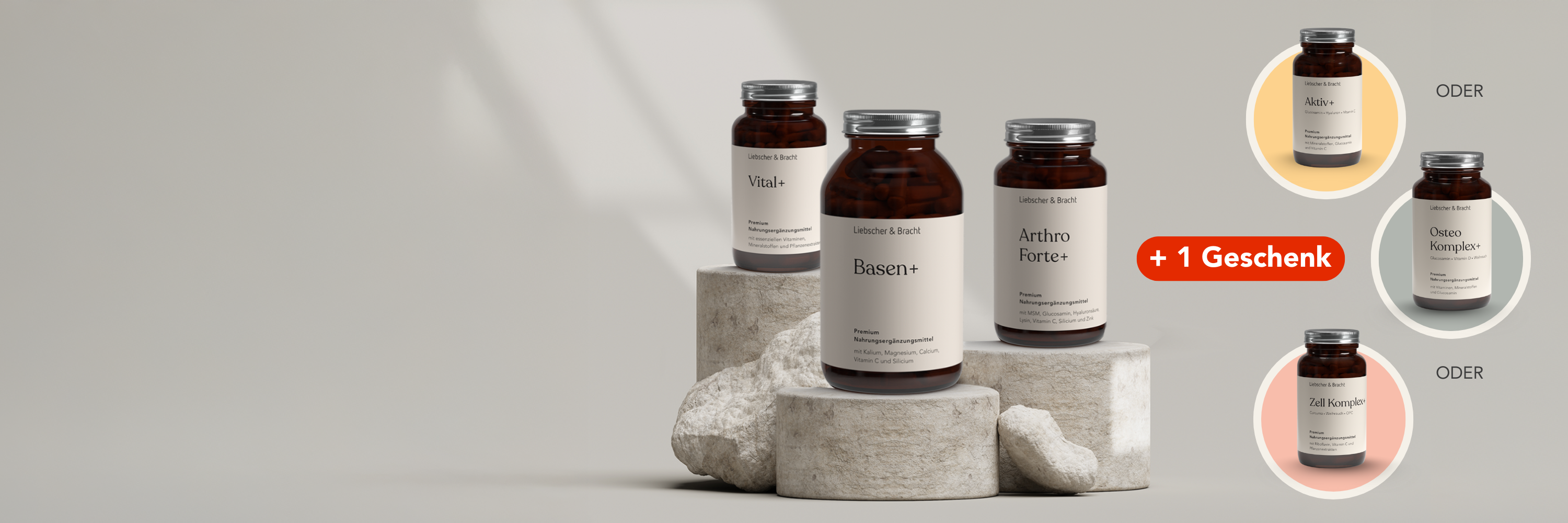 Vier braune Ergänzungsflaschen mit den Aufschriften Vitale+, Basen+ und Arthro Forte+ stehen auf Steinsockeln. Auf der rechten Seite werden drei Flaschenoptionen als Geschenkauswahl gezeigt, hervorgehoben durch ein rotes +1 Geschenk-Etikett.