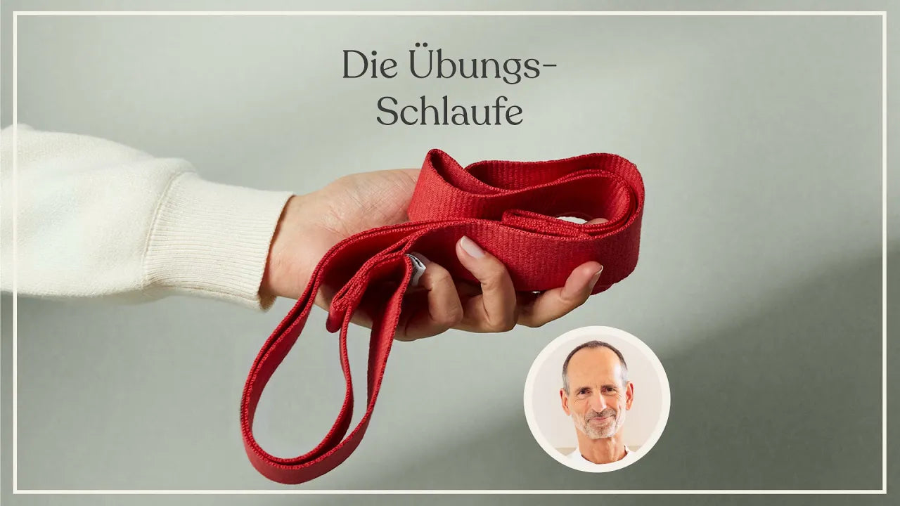 Eine Hand hält ein rotes Übungsband mit Schlaufen. Der deutsche Text darüber lautet Die Übungs-Schlaufe. In der unteren rechten Ecke befindet sich das kleine Porträt eines älteren Mannes mit sanfter Miene.