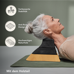Ältere Frau liegt mit dem Nacken auf einem ergonomischen Nackenkissen aus Holz und Schaumstoff. Text hebt verbesserte Stabilität, Anti-Rutsch-Design und hochwertiges Naturholz hervor.