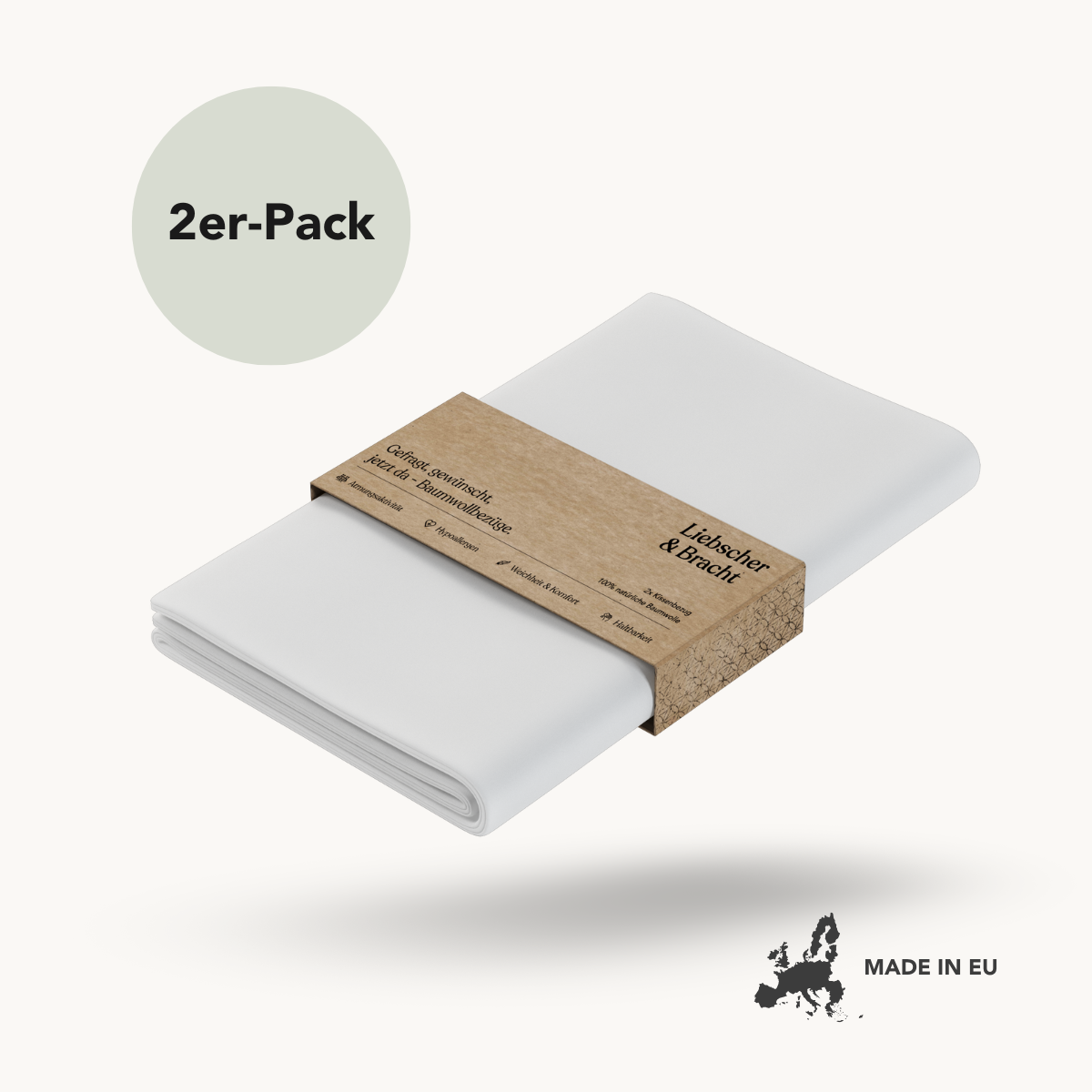 Satz von zwei gefalteten weißen Baumwoll-Kissenbezügen von Liebscher & Bracht, umwickelt mit einer braunen Papierbanderole. Oben im Kreis steht "2er-Pack", unten rechts "Made in EU" mit einer Europakarte.