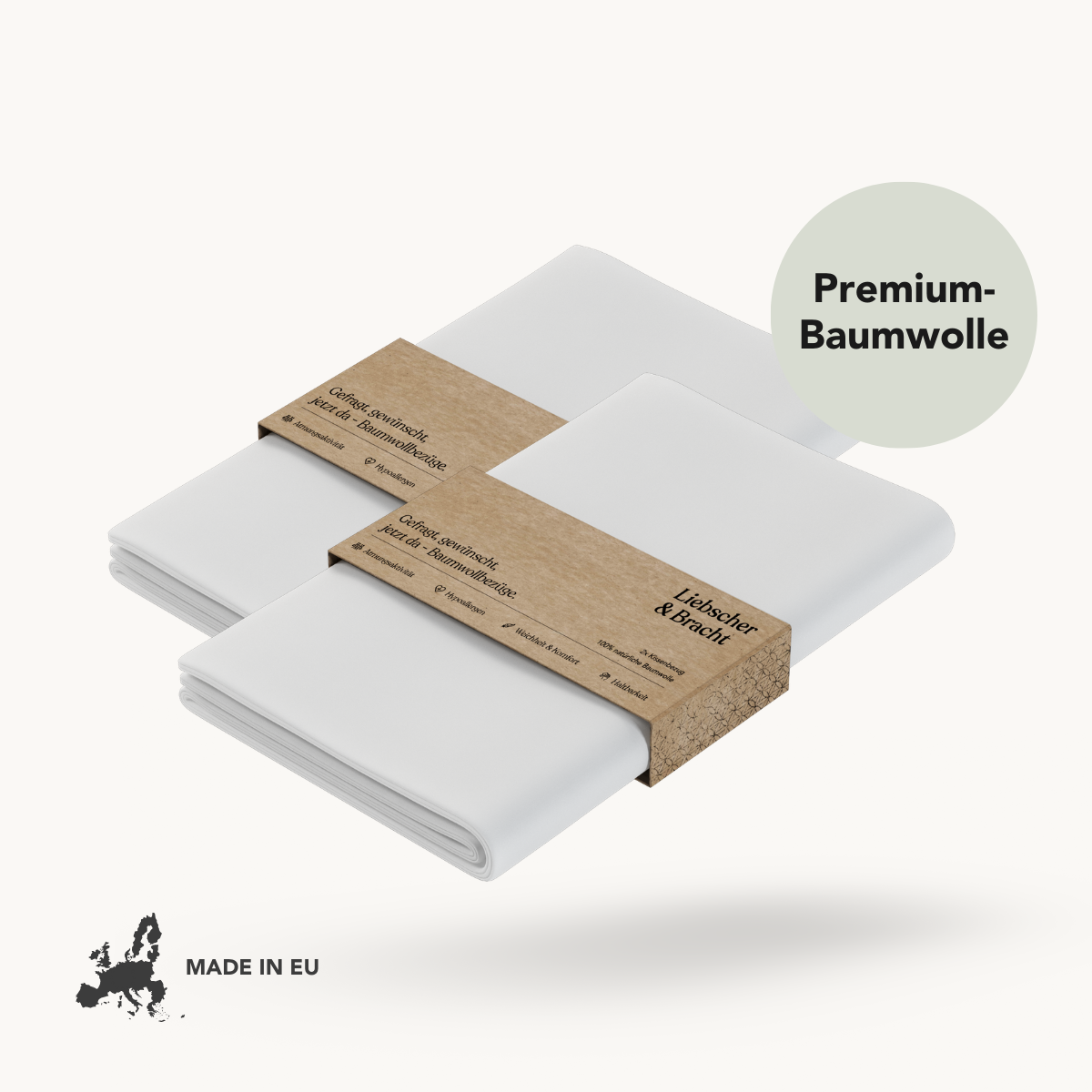 Zwei gefaltete weiße Kissenbezüge "Vorteilsset: Baumwoll-Kissenbezug" von Liebscher & Bracht, eingewickelt in braune Kraftbänder, die mit der Marke und einem Premium-Baumwollstempel versehen sind, sowie einem Made in EU-Etikett mit einer Europakarte.