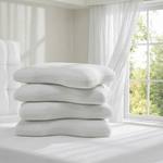 Vier Liebscher & Bracht Vorteilsset: Baumwoll-Kissenbezug Koffer in Weiß stehen auf einem Bett in einem hellen Schlafzimmer mit luftigen weißen Wänden und durchsichtigen Vorhängen, durch die das Sonnenlicht durch das Fenster fällt.