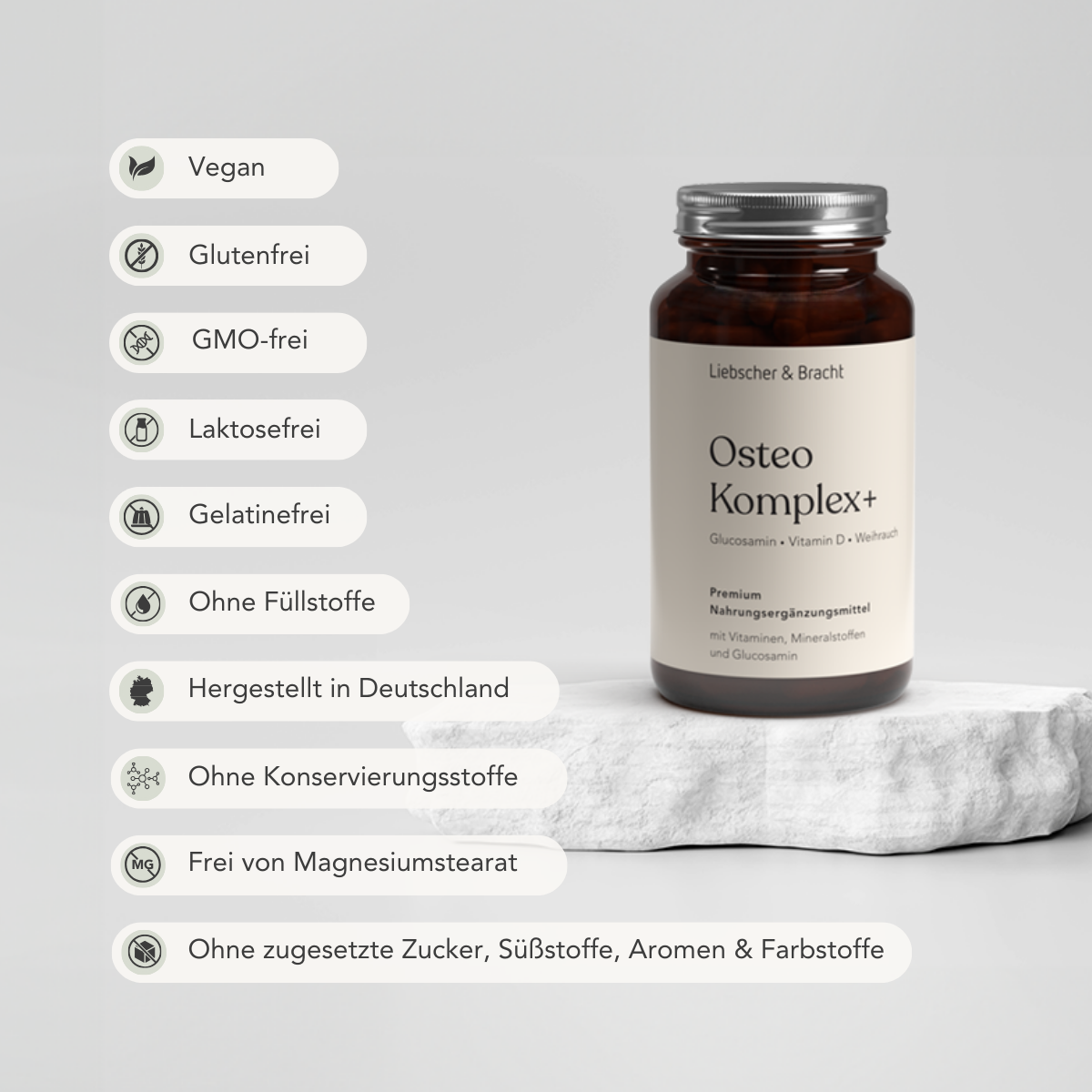 Eine braune Glasflasche von Liebscher & Bracht Osteo Komplex+ für 2 Monate mit Vitamin D steht auf einem weißen Stein. Icons auf der linken Seite heben Merkmale hervor: vegan, umweltfreundlich, glutenfrei, ohne Gentechnik, laktosefrei und mehr.