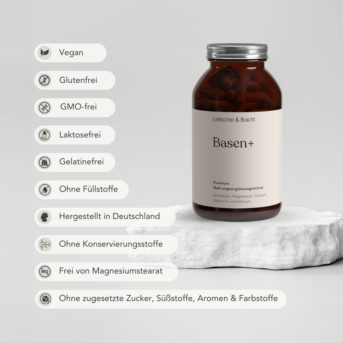 Eine braune Flasche mit der Aufschrift Basen+ für 2 Monate von Liebscher & Bracht steht auf einer weißen Steinplatte. Icons und Text heben hervor: mit Magnesium, vegan, gluten-, gentechnik-, laktose- und gelatinefrei, made in Germany, ohne Konservierungsstoffe und Zuckerzusatz.