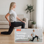 Eine Frau macht zu Hause einen Ausfallschritt, während in einem Einblender ein Livestream mit dem Titel „Sonntags-Training mit Roland“ aus der Liebscher & Bracht-App zu sehen ist, in dem ein Mann dieselbe Übung in einer ähnlichen Umgebung vorführt.