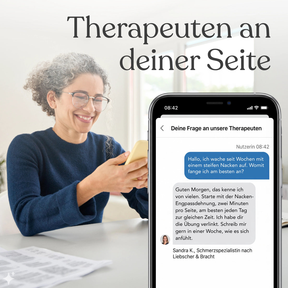 Eine lächelnde Frau mit lockigem Haar und Brille hält ein Smartphone in der Hand, auf dessen Bildschirm die „Liebscher & Bracht“-App von Liebscher & Bracht zu sehen ist. Dort erscheint neben dem deutschen Text „Therapeuten an deiner Seite“ ein Chat mit einem Therapeuten über Nackenschmerzen.