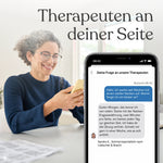 Eine lächelnde Frau mit lockigem Haar und Brille hält ein Smartphone in der Hand, auf dessen Bildschirm die „Liebscher & Bracht“-App von Liebscher & Bracht zu sehen ist. Dort erscheint neben dem deutschen Text „Therapeuten an deiner Seite“ ein Chat mit einem Therapeuten über Nackenschmerzen.