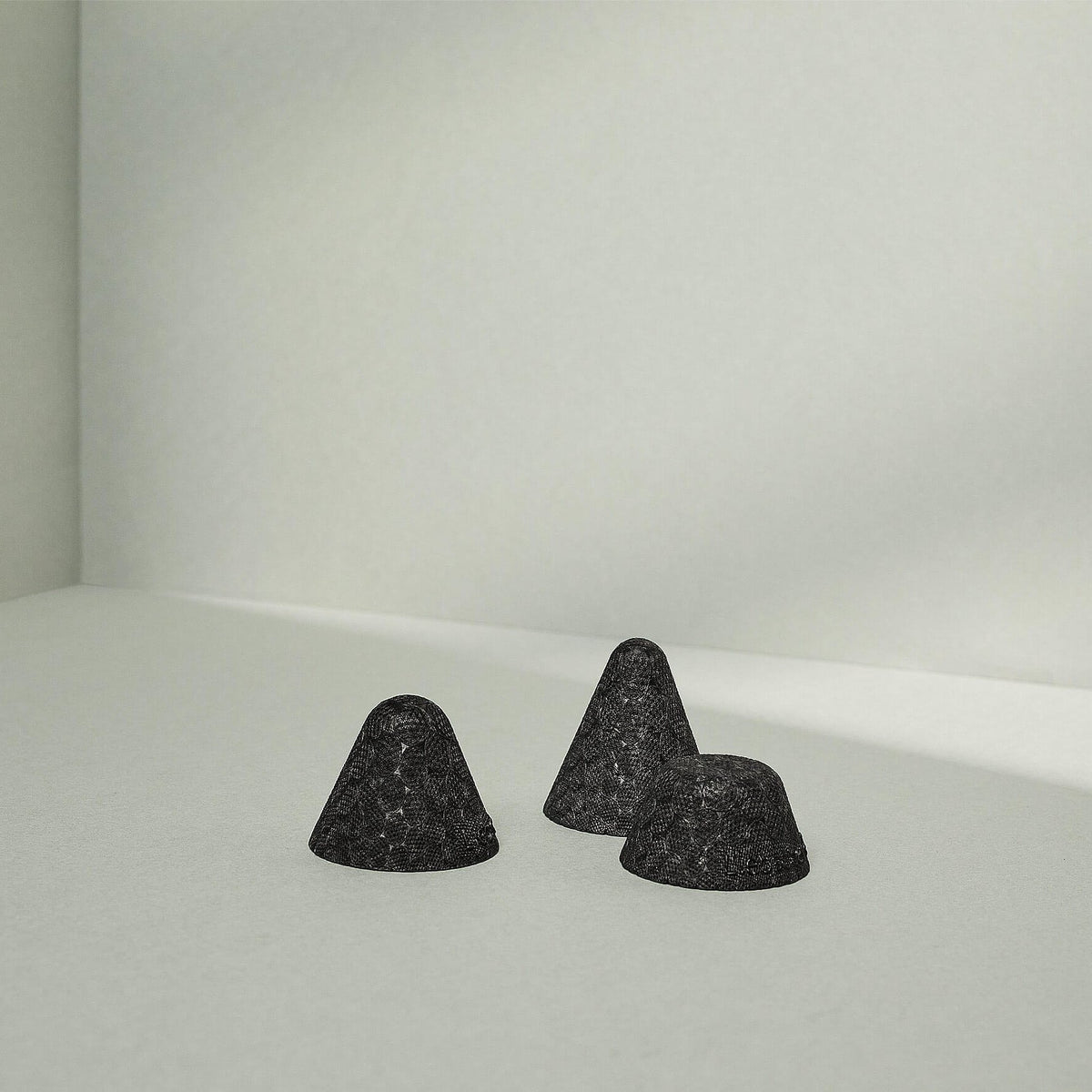Drei kleine, schwarze Drücker-Aufsätze Weich von Liebscher & Bracht ruhen auf einer hellgrauen Fläche vor einem minimalistischen Hintergrund, perfekt für gezielte Druck-Stimulation empfindlicher Punkte mit weichen Schatten.