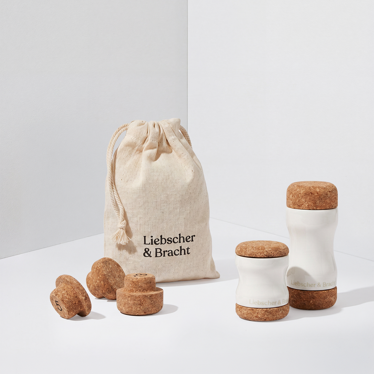 „Der Kieferretter“ von Liebscher & Bracht – ein Set aus Massagewerkzeugen und Stoppern aus Kork und weißer Keramik zur Linderung von CMD-Symptomen, Kieferschmerzen oder Zähneknirschen – liegt neben einem beigen „Liebscher & Bracht“-Beutel mit Kordelzug auf einem schlichten weißen Hintergrund.