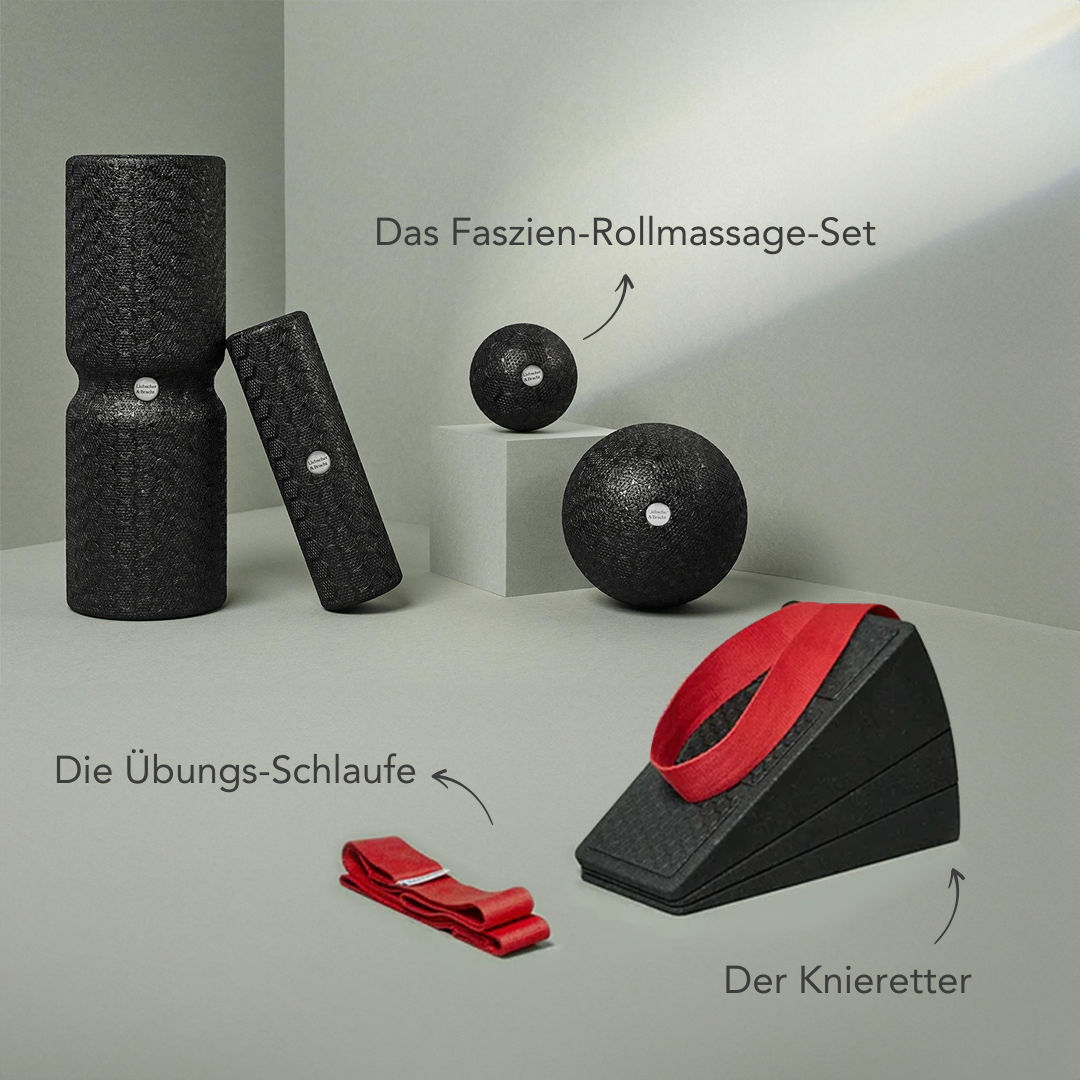 Das Dein Knie-Paket von Liebscher & Bracht mit schwarzen Faszienrollen und Massagebällen, einer roten Trittschlaufe und einem schwarzen Knieretter-Kniekeil mit rotem Gurt wird auf hellen Sockeln mit deutschen Etiketten präsentiert.
