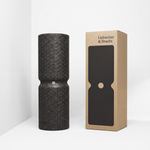 Eine MAXI-Faszienrolle mit Wirbelsäulenentlastung von Liebscher & Bracht steht aufrecht neben ihrer braunen Verpackung, auf der eine schwarze Rollensilhouette abgebildet ist; beides ist vor einem weißen Hintergrund zu sehen.