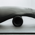Eine Nahaufnahme des Beins einer Person in Sportbekleidung, die auf einer Yogamatte die „Liebscher & Bracht MAXI-Faszienrolle mit Wirbelsäulen-Entlastung“ verwendet, was auf eine Muskelmassage oder Physiotherapie für den Rücken hindeutet.