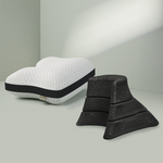 Das Liebscher & Bracht Kissen + Nackenretter Set besteht aus einem weißen, konturierten Kissen mit einem schwarzen Band und vier schwarzen, strukturierten Schaumstoffkeilen, die auf einer hellgrünen Fläche vor einer passenden Wand angeordnet sind.