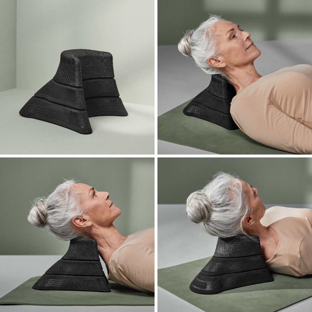 Eine Frau mit grauem Haar in einem Dutt demonstriert das Liebscher & Bracht Kissen + Nackenretter Set, indem sie den ergonomischen schwarzen Stützkeil auf einer Matte benutzt, um ihren oberen Rücken, Nacken und Kopf zu entlasten. Nahaufnahmen zeigen die strukturierte Oberfläche des Keils.