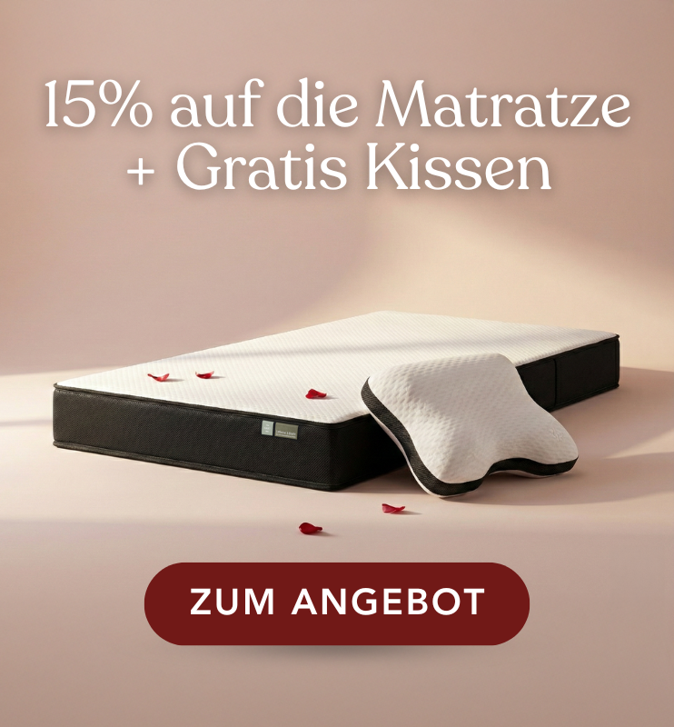 Eine Matratze und ein Kissen mit verstreuten Rosenblättern sind auf einem beigen Hintergrund abgebildet. Der Text darüber bietet 15% auf die Matratze + Gratis Kissen. Ein roter Button darunter lautet Zum Angebot.