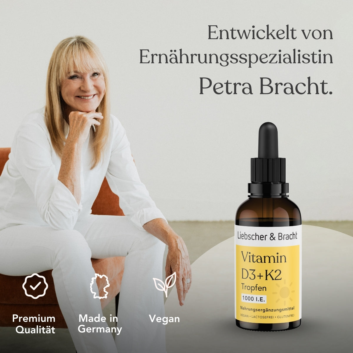 Eine lächelnde Frau mit hellem Haar in weißer Kleidung sitzt neben einer Flasche mit der Aufschrift Liebscher & Bracht Vitamin D3+K2VITAL® Tropfen. Der Text hebt Premiumqualität, vegan, Made in Germany hervor, mit einer deutschen Produktbeschreibung im Hintergrund.