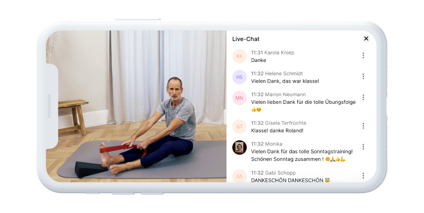 Ein Mann in Trainingskleidung sitzt auf einer Yogamatte und streckt seine Beine in einem hellen Raum, während auf der rechten Seite eines Smartphone-Bildschirms ein Live-Chat mit verschiedenen Kommentaren erscheint.