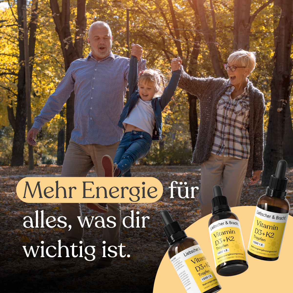 Ein älteres Paar schaukelt ein lächelndes Mädchen zwischen sich in einem sonnigen Herbstpark. Darunter sind Flaschen mit Vitamin D3+K2VITAL® Tropfen von Liebscher & Bracht zu sehen, deren Text auf mehr Energie für das Wesentliche hinweist.