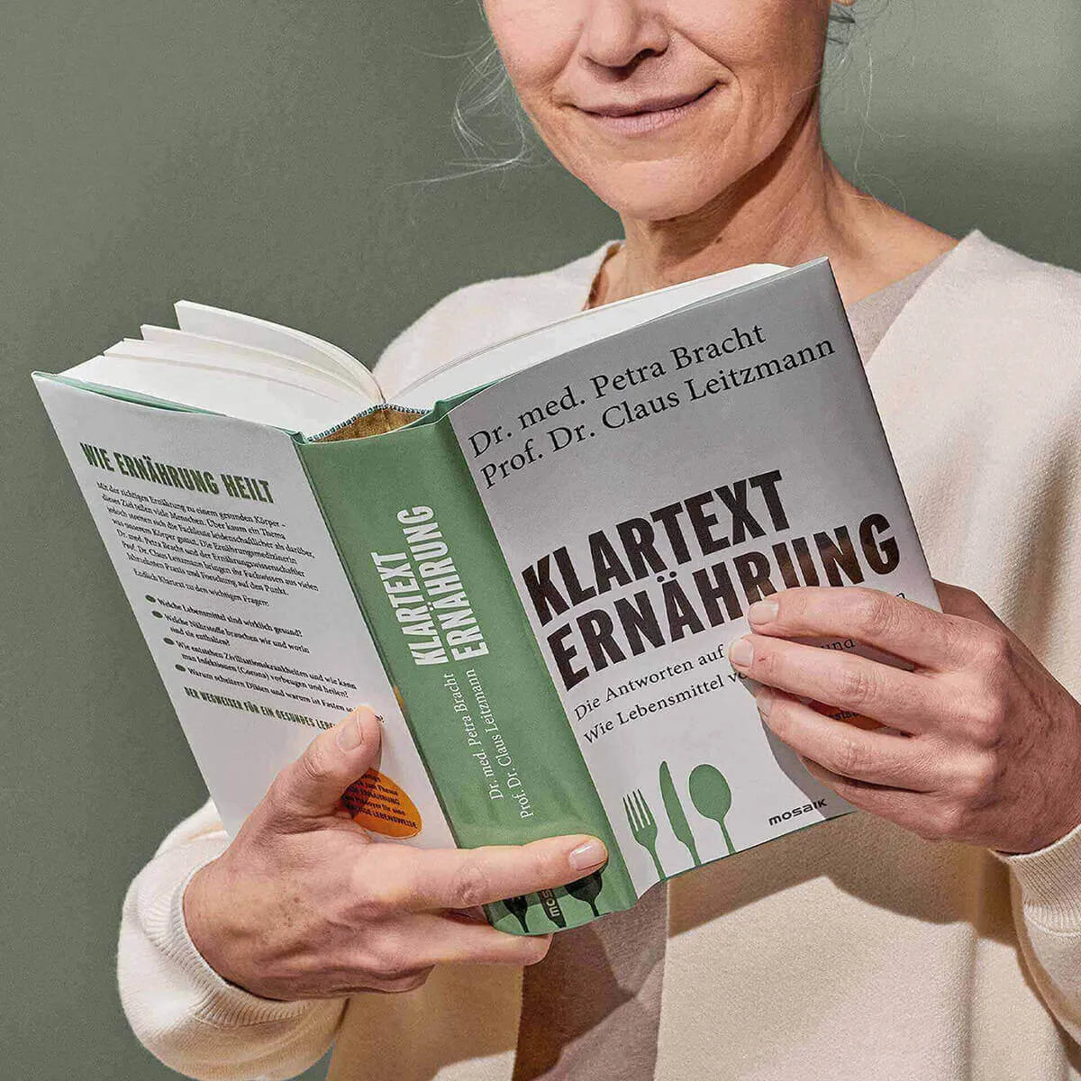 Eine Person mit dem Klartext Ernährung: Die Antworten auf alle wichtigen Fragen von Liebscher & Bracht, mit einem hellgrünen Einband, auf dem Gabel, Messer und Löffel abgebildet sind.