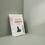 Drei Exemplare des Buches "Rolle dich schmerzfrei" von Liebscher & Bracht stehen aufrecht vor einem grauen Hintergrund. Auf dem Umschlag mit dem Thema "Natürliche Schmerzbehandlung" sind ein Mann und schwarze Massagerollen mit roter und schwarzer Schrift abgebildet.