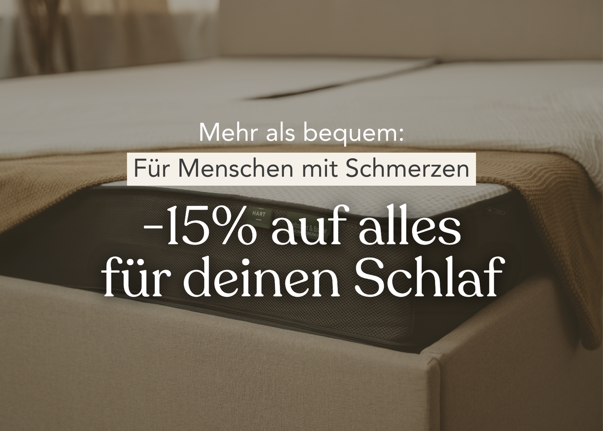 Ein Bett mit beiger Bettwäsche und einer Decke, mit deutschem Text: Mehr als bequem: Für Menschen mit Schmerzen -15% auf alles für deinen Schlaf. Der Fokus liegt auf einer Matratzenecke.