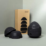 Drei schwarze, strukturierte Schaumstoff-Massagekuppeln und ein hellbrauner Kasten von Liebscher & Bracht mit der Aufschrift "Der ISG-Ischias-Retter", der die Beweglichkeit im Hüftbereich verbessern soll, wobei der Kasten gestapelte schwarze Formen aufweist, die zu den Kuppeln passen.