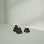 Drei schwarze, kegelförmige Drücker-Aufsätze Mittel von Liebscher & Bracht mit weißen Sprenkeln ruhen auf einer hellgrauen Oberfläche - ideal für Anfänger oder Fortgeschrittene, die eine sanfte Druckstimulation suchen.