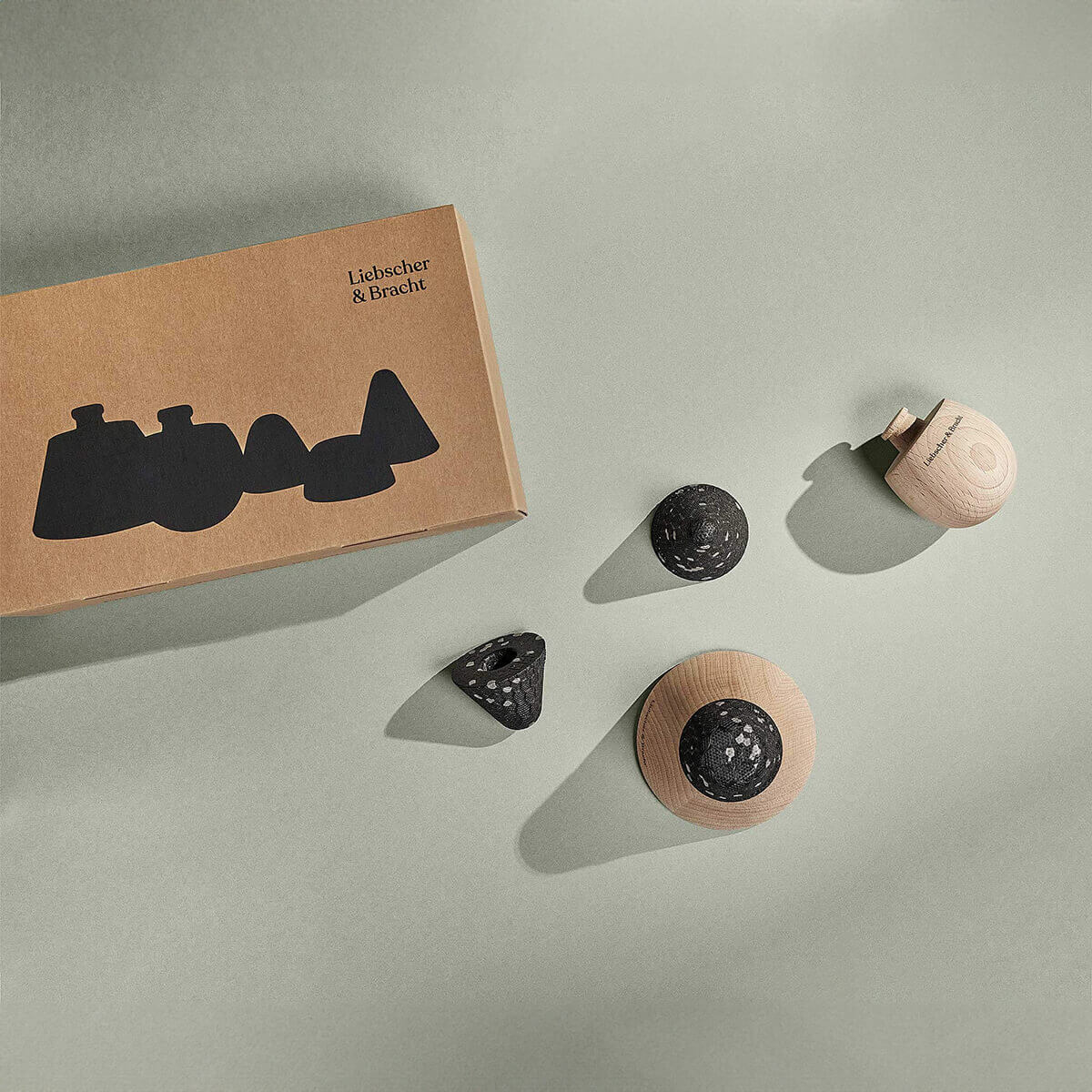 Das Liebscher & Bracht Angebots-Paket enthält neben einer braunen Markenbox vier unterschiedlich geformte Massagewerkzeuge aus Holz in den Farben Natur und Schwarz - perfekt für die gezielte Entlastung im Rahmen Ihres Faszienrollen-Sets.