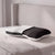 Ein ergonomisch geformtes Liebscher & Bracht-Kissen mit einem zweigeteilten, weiß-schwarzen Bezug, das auf einem Bett liegt und für eine bequeme Rückenlage sorgt.