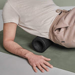 Eine Person in Beige nutzt die Liebscher & Bracht MAXI-Faszienrolle mit Wirbelsäulen-Entlastung in der Seitenlage zur Muskelmassage - ideal für große Körperflächen und zur Unterstützung entlang der Wirbelsäule.