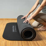 Eine Person kniet auf einem Holzboden und rollt die Liebscher & Bracht Rolands Übungsmatte auf. Nur ihre Arme und Beine sind zu sehen, der rutschfeste Untergrund der Matte sorgt für Stabilität vor dem hellen Hintergrund.