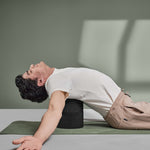 Ein Mann lehnt mit geschlossenen Augen und ausgebreiteten Armen auf dem Liebscher & Bracht Der Rückenretter, der in einer ruhigen Studioumgebung für Mobilisierung und Entspannung der Rückenmuskulatur wirbt.